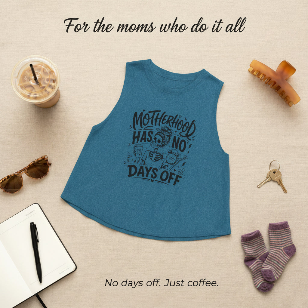 Blue Motherhood Has No Days Off crop tank with iced coffee, glasses, keys, and hair clip styling props.