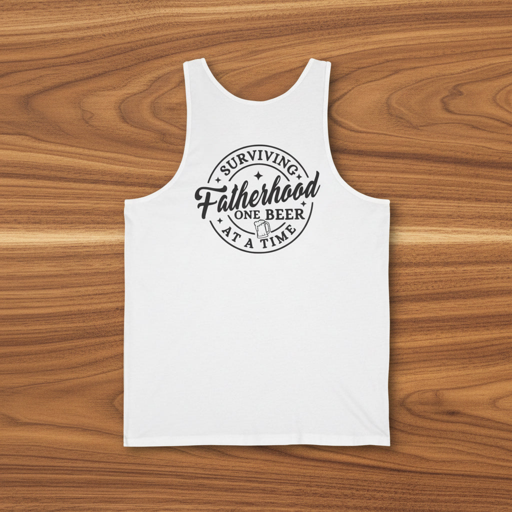 White Surviving Fatherhood One Beer at a Time tank top shown on a wooden surface as a Father’s Day gift.
