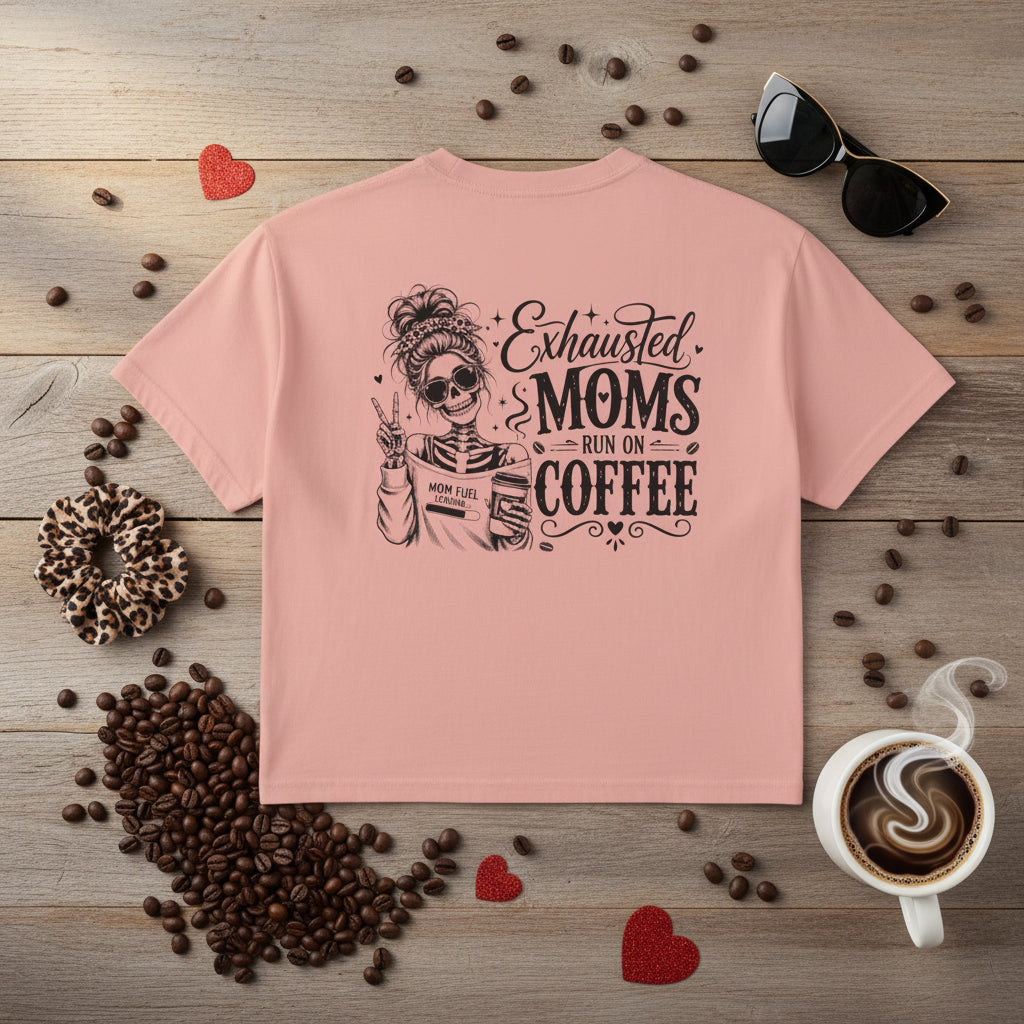 Pink women’s boxy cropped tee with black Exhausted Moms Run On Coffee graphic on the back.