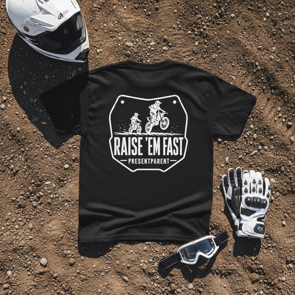 Black men’s dirtbike dad t-shirt with white Raise ’Em Fast father and child motocross graphic on a dirt background.