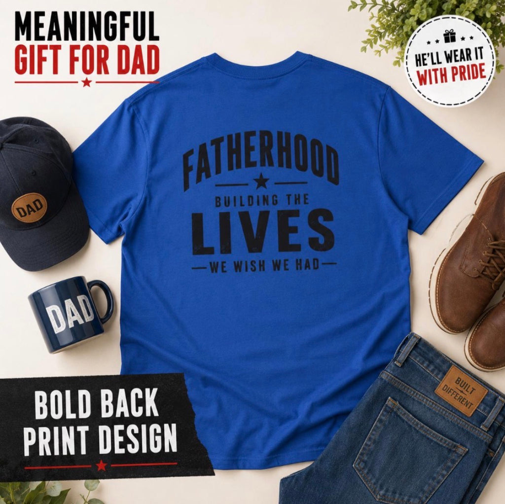Royal blue Fatherhood graphic T-shirt flat lay with cap, mug, and shoes, featuring Building the Lives We Wish We Had back print for dads.