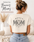 Woman wearing a white t-shirt with 'Bonus Mom lifestyle' print, sitting on a couch.