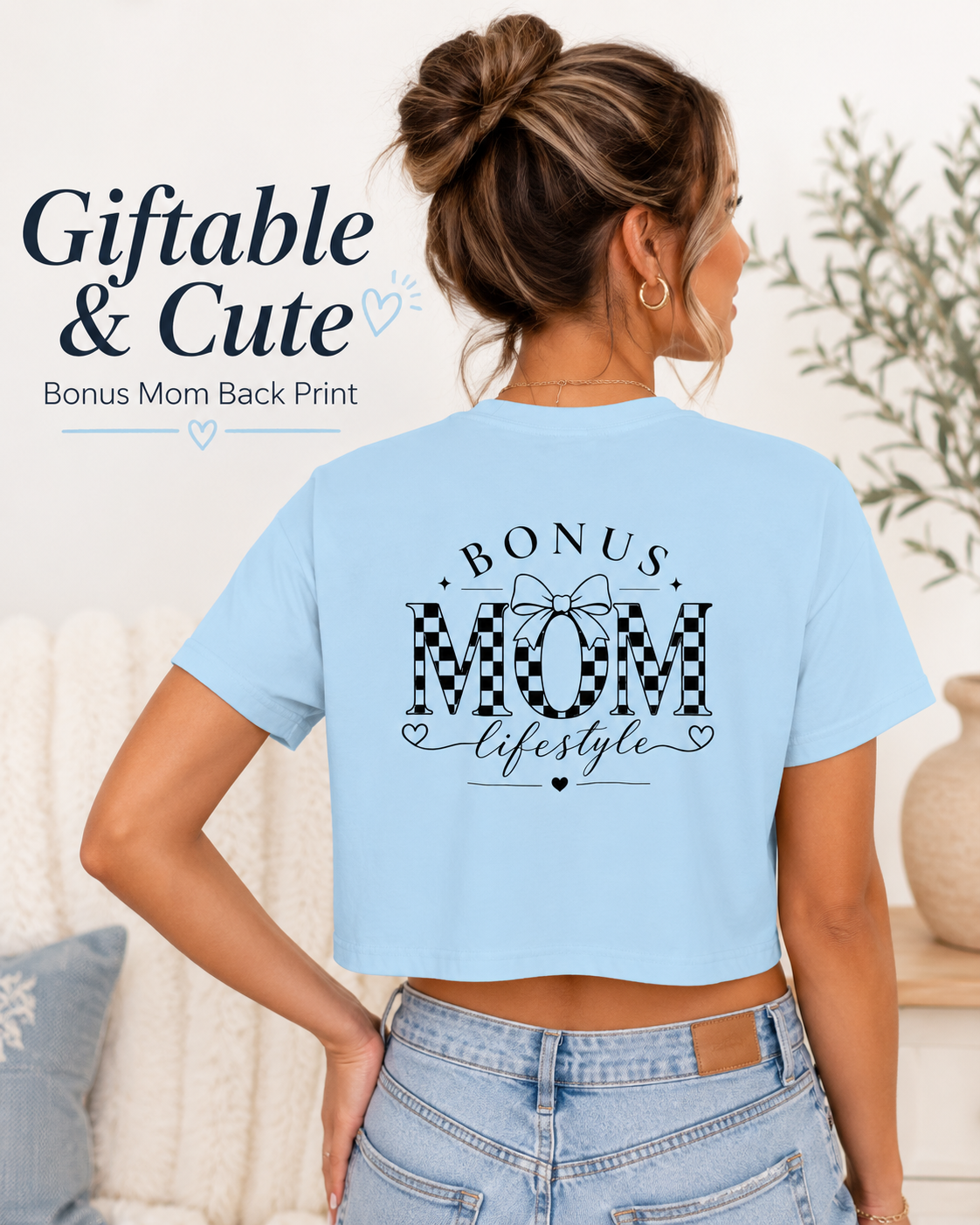 Woman wearing a light blue t-shirt with 'Bonus Mom lifestyle' print, standing in a home setting.