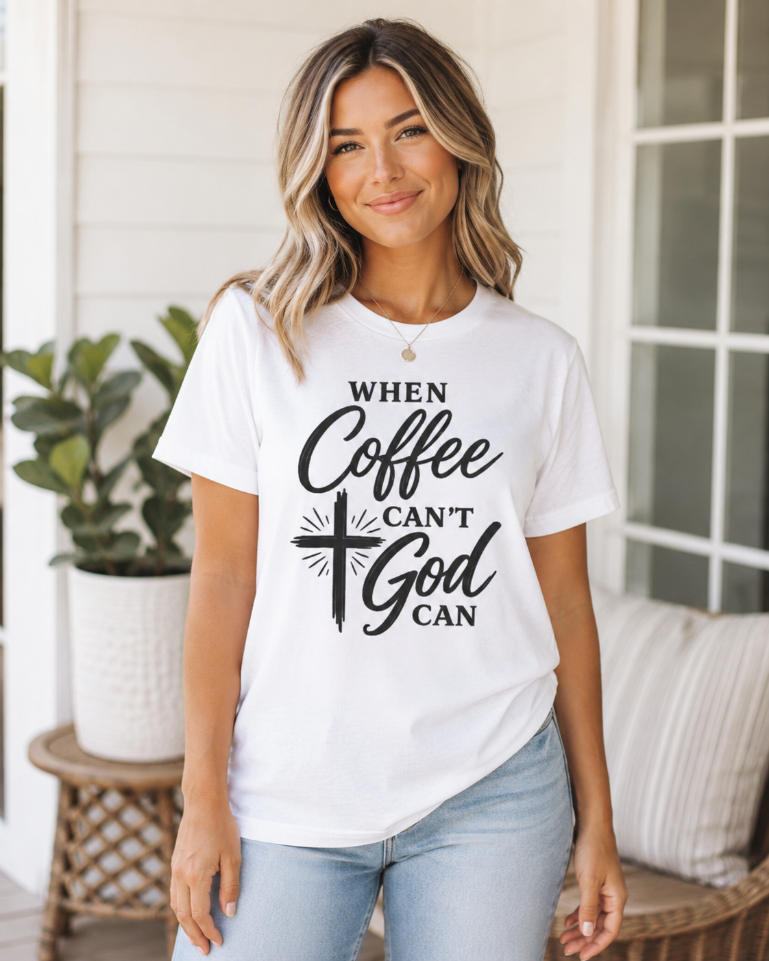 A woman wearing a white graphic t-shirt with the text 'WHEN Coffee CAN'T God CAN' and a black cross design, paired with light blue jeans, standing on a porch.