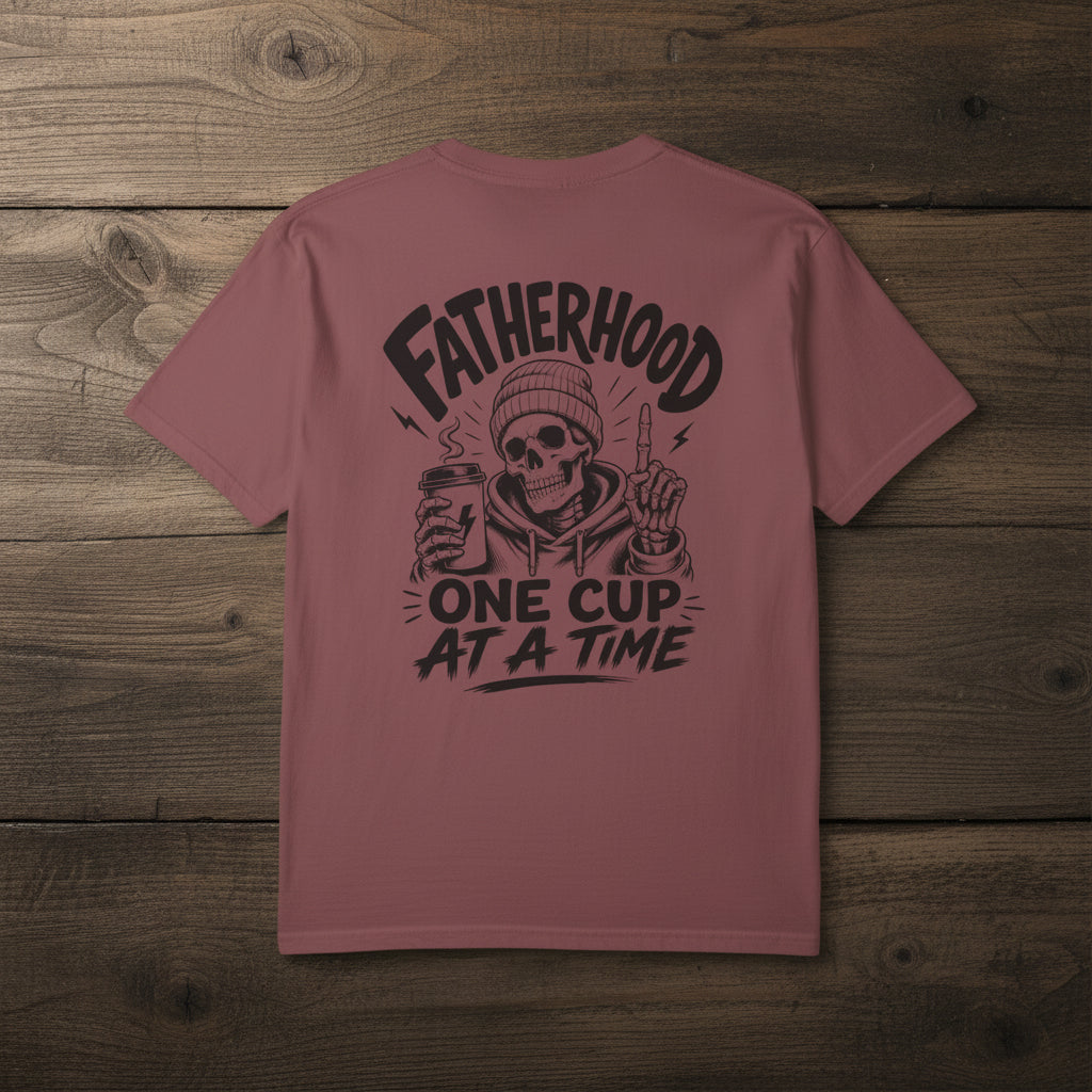 Maroon Fatherhood Club t-shirt with black Fatherhood One Cup At A Time coffee dad graphic on a woodgrain background.