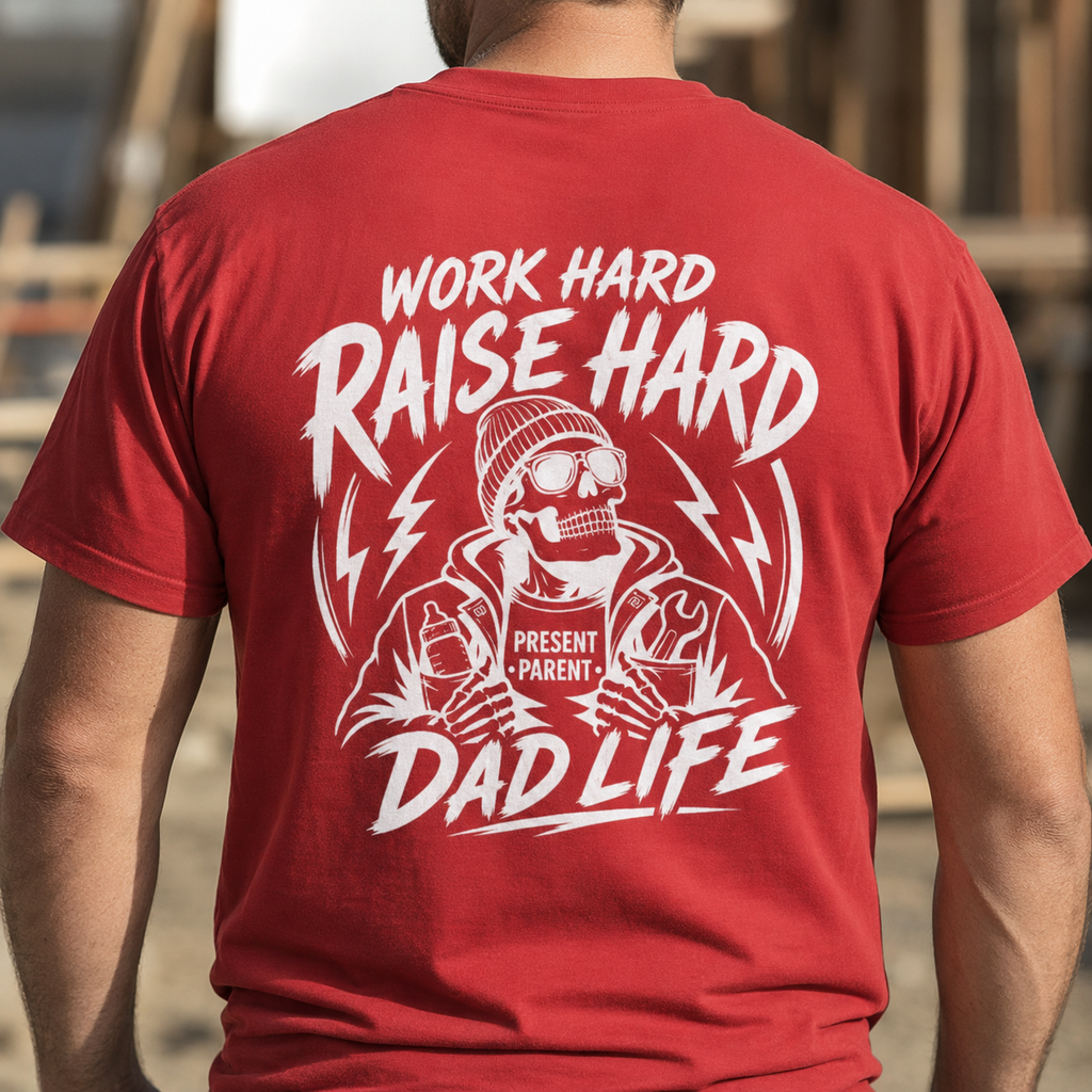 A man viewed from behind wearing a red t-shirt with a large white graphic print that reads 'WORK HARD RAISE HARD DAD LIFE' and features a skeleton dad holding a coffee mug that says 'PRESENT PARENT'.