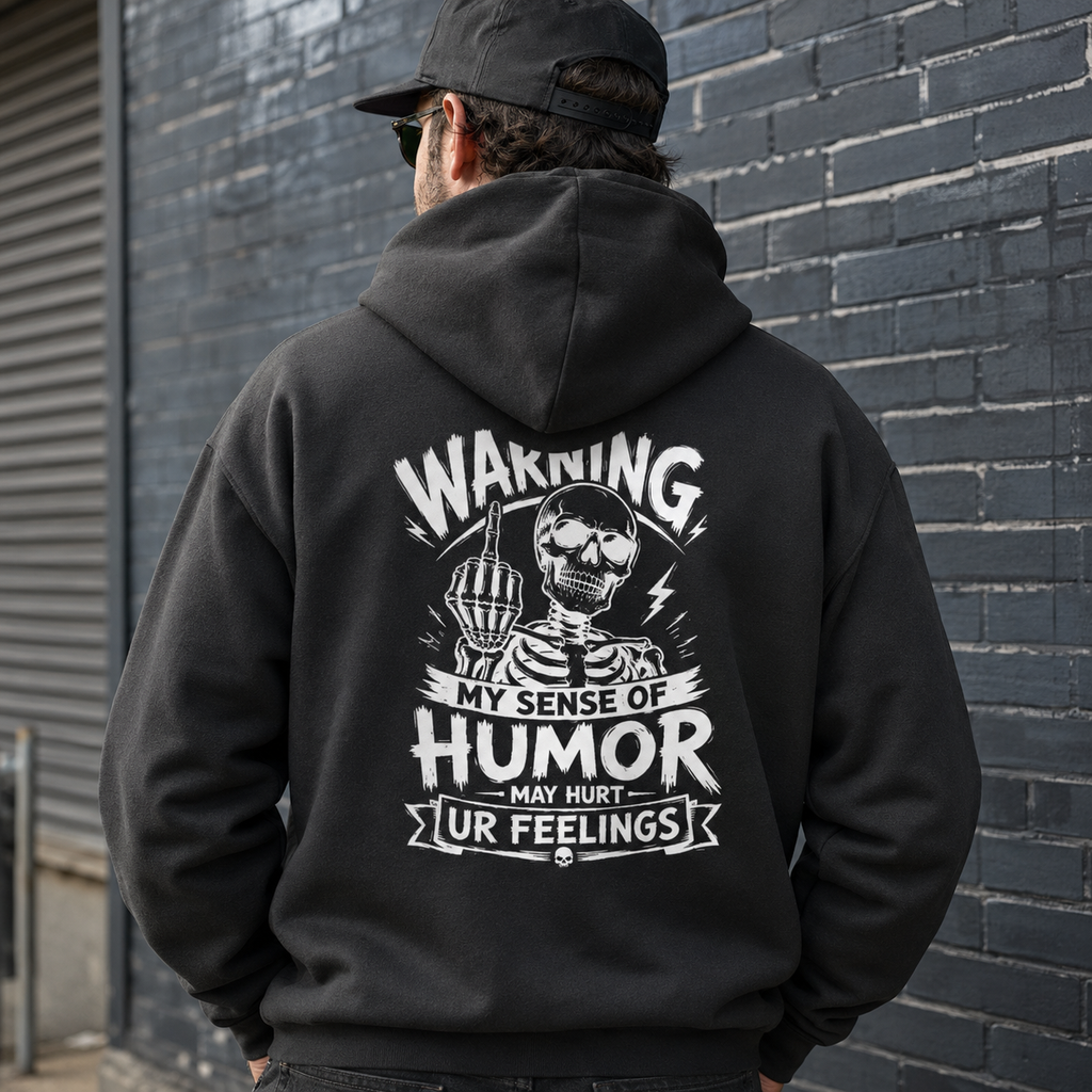 Charcoal black skeleton humor hoodie worn in lifestyle setting, Warning My Sense of Humor May Hurt Ur Feelings back print sweatshirt, sarcastic graphic pullover for men, edgy streetwear hoodie, funny offensive joke apparel, casual gift hoodie for dad, husband, boyfriend, or friend.