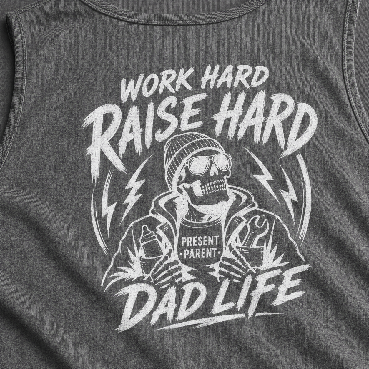 Close-up of a dark gray sleeveless tank top with a large white graphic print featuring a skeleton dad wearing a beanie and sunglasses, with the text 'WORK HARD RAISE HARD DAD LIFE' and 'PRESENT PARENT'.